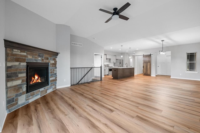 unfurnished living room with ceiling fan, light hardwood / wood-style floors, lofted ceiling, and a fireplace