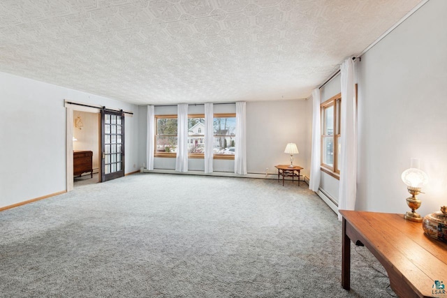 interior space featuring a barn door, carpet floors, a textured ceiling, and a baseboard heating unit