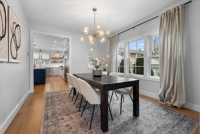 dining space featuring light wood-type flooring and a notable chandelier