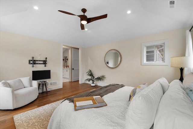 bedroom with ensuite bath, ceiling fan, hardwood / wood-style floors, and vaulted ceiling