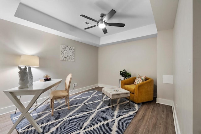 home office with hardwood / wood-style floors, a tray ceiling, and ceiling fan