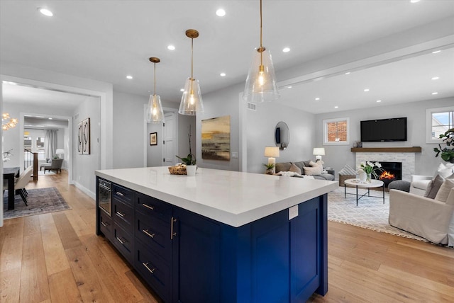 kitchen with decorative light fixtures, light hardwood / wood-style floors, a kitchen island, and blue cabinetry