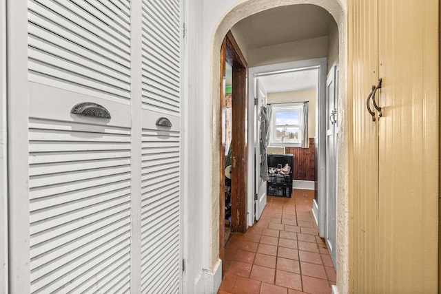 hall featuring tile patterned flooring and wooden walls