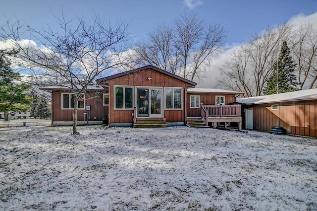 snow covered back of property featuring a deck