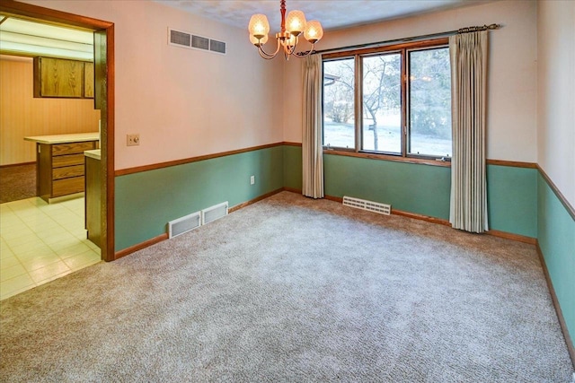 unfurnished room featuring light colored carpet and a notable chandelier