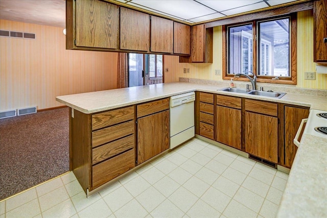 kitchen with kitchen peninsula, sink, light colored carpet, and white appliances