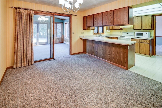 kitchen featuring white appliances, light carpet, sink, kitchen peninsula, and a chandelier