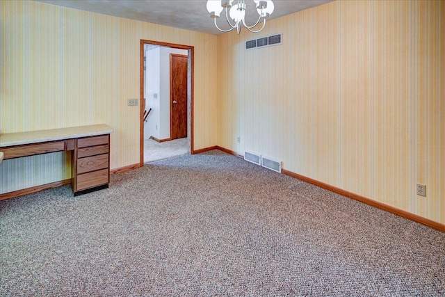 carpeted spare room with a chandelier