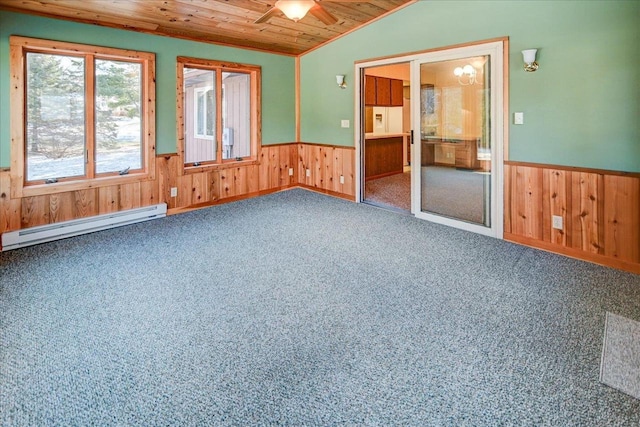 carpeted empty room with a baseboard heating unit, wooden walls, vaulted ceiling, ceiling fan, and wood ceiling