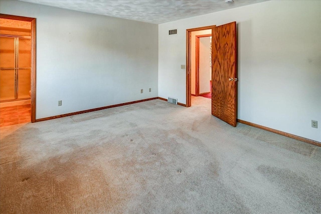 unfurnished room with a textured ceiling and light carpet