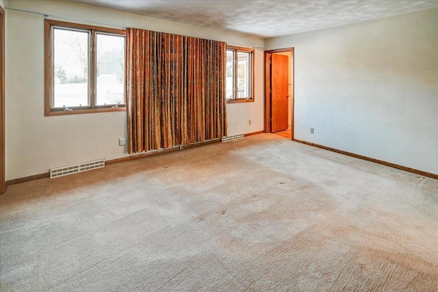 unfurnished room with a textured ceiling and light colored carpet