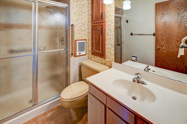 bathroom with tile patterned floors, heating unit, toilet, vanity, and a shower with shower door