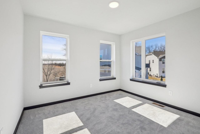 unfurnished room featuring baseboards, visible vents, and carpet flooring