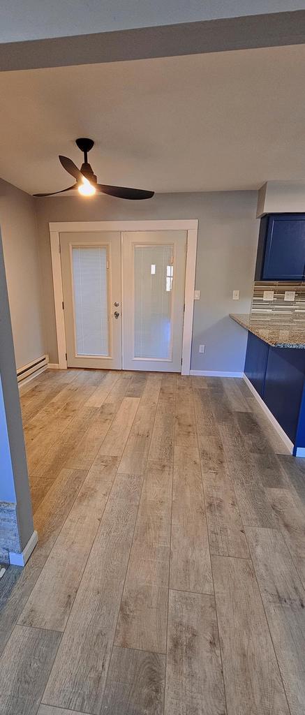 interior space with light hardwood / wood-style floors, a baseboard radiator, and ceiling fan