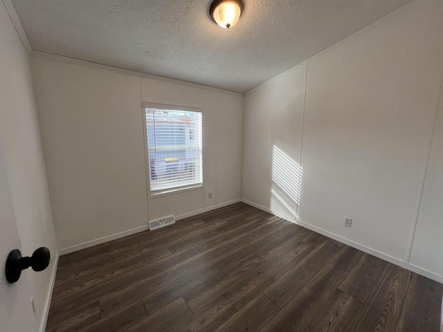 spare room featuring a textured ceiling, dark hardwood / wood-style flooring, and ornamental molding