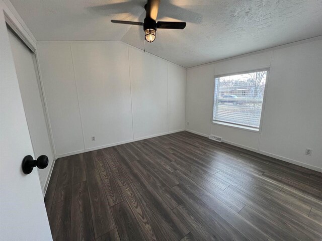 unfurnished bedroom featuring a textured ceiling, dark hardwood / wood-style floors, vaulted ceiling, and ceiling fan