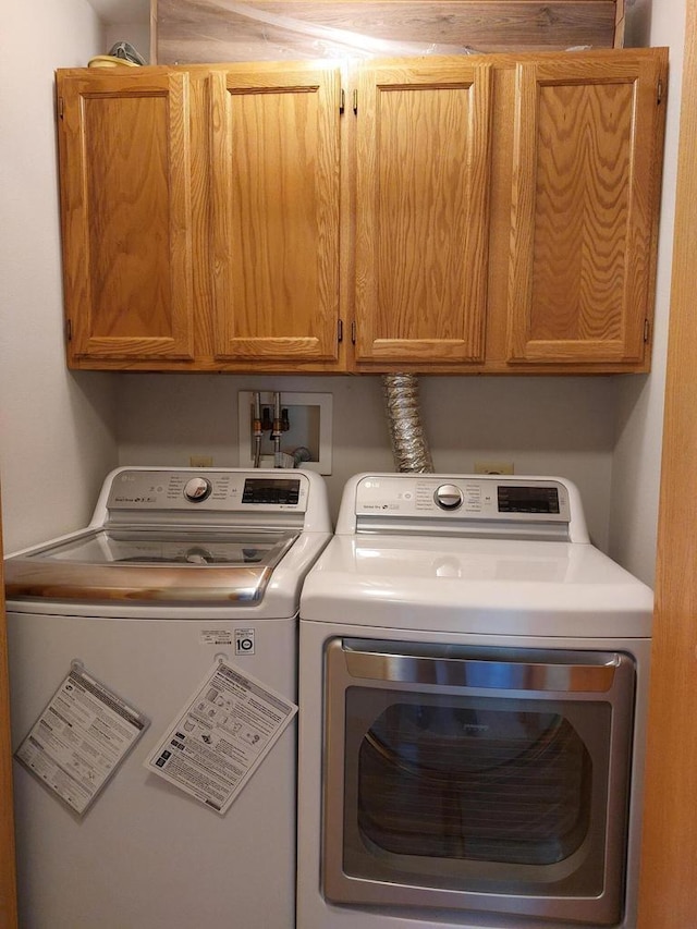 laundry room with washing machine and clothes dryer and cabinets