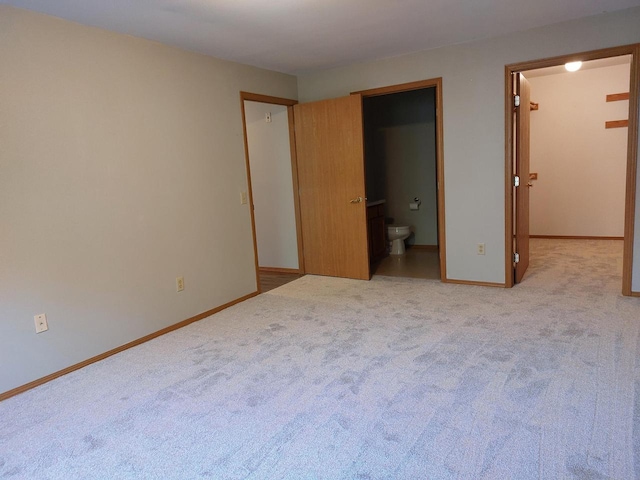 unfurnished bedroom featuring light carpet and connected bathroom