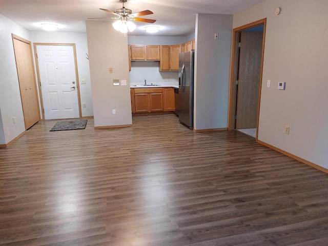 unfurnished living room with ceiling fan, sink, and dark wood-type flooring