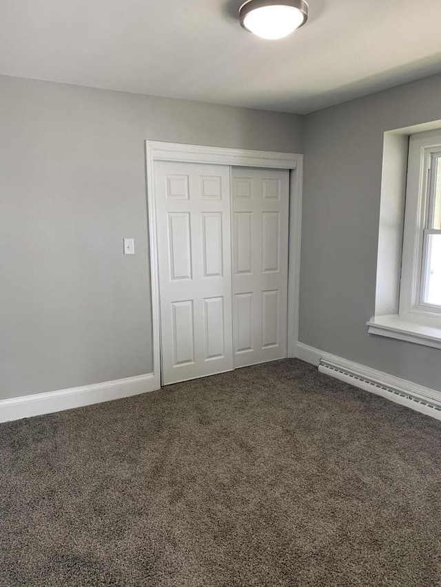 unfurnished bedroom with baseboard heating, a closet, and carpet floors