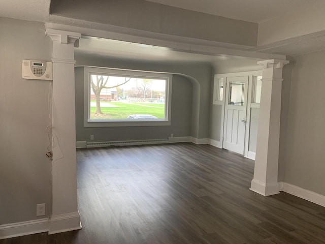 unfurnished room with decorative columns, dark wood-type flooring, and a baseboard heating unit