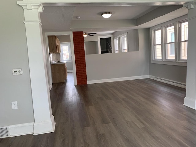 unfurnished room with ceiling fan, dark hardwood / wood-style flooring, ornate columns, and baseboard heating