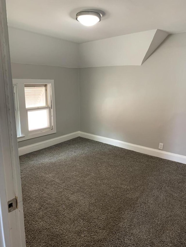 unfurnished room featuring carpet and vaulted ceiling