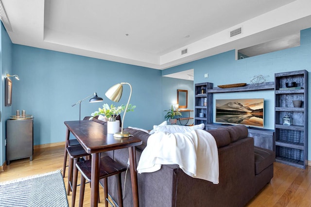 living room with a tray ceiling and wood-type flooring