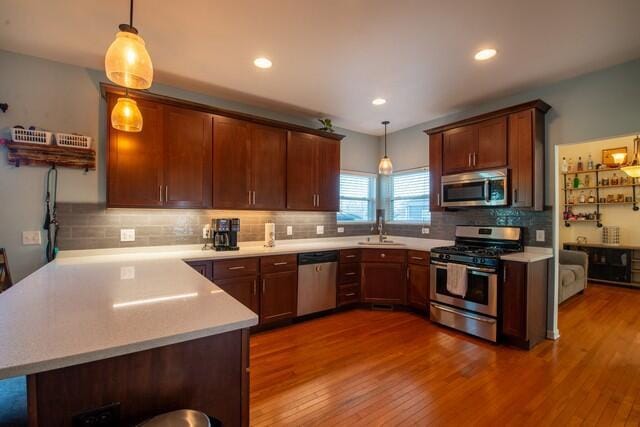 kitchen with pendant lighting, dark hardwood / wood-style flooring, and appliances with stainless steel finishes