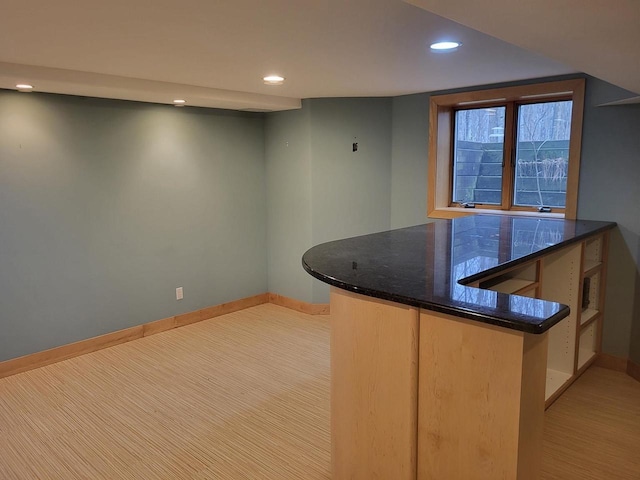 kitchen with kitchen peninsula and dark stone counters