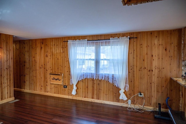 unfurnished room with dark wood-type flooring and wooden walls