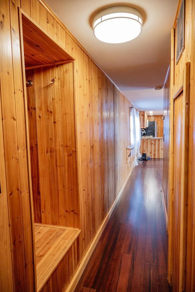 corridor with wooden walls and dark hardwood / wood-style floors