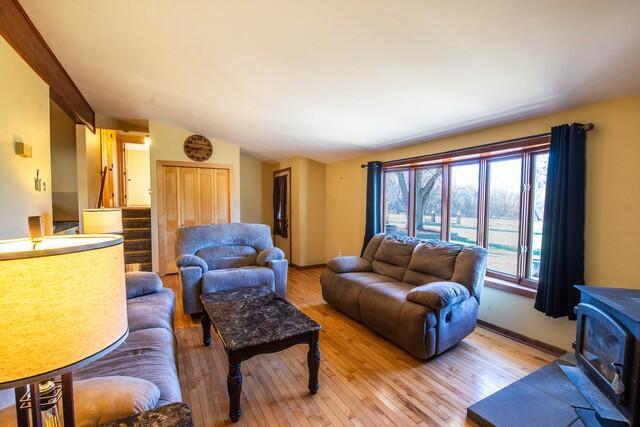 living room featuring hardwood / wood-style floors, a wood stove, and vaulted ceiling