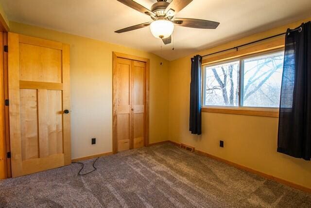 unfurnished bedroom featuring carpet, ceiling fan, and a closet