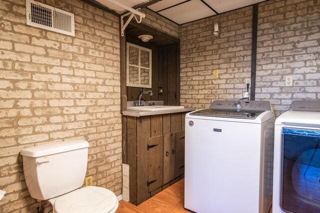 washroom featuring washer and dryer and brick wall