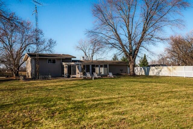 rear view of property with a sunroom and a lawn