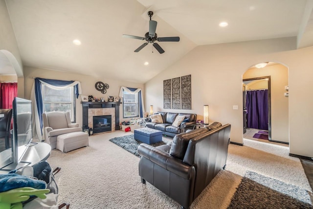 living room featuring a tiled fireplace, ceiling fan, light colored carpet, and lofted ceiling