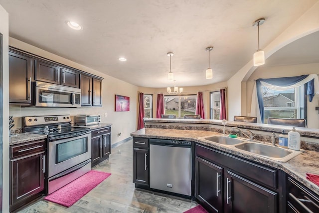 kitchen with sink, stainless steel appliances, a notable chandelier, pendant lighting, and hardwood / wood-style flooring