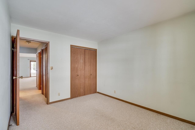 unfurnished bedroom featuring light colored carpet and a closet