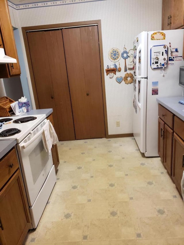 kitchen featuring ventilation hood and white appliances