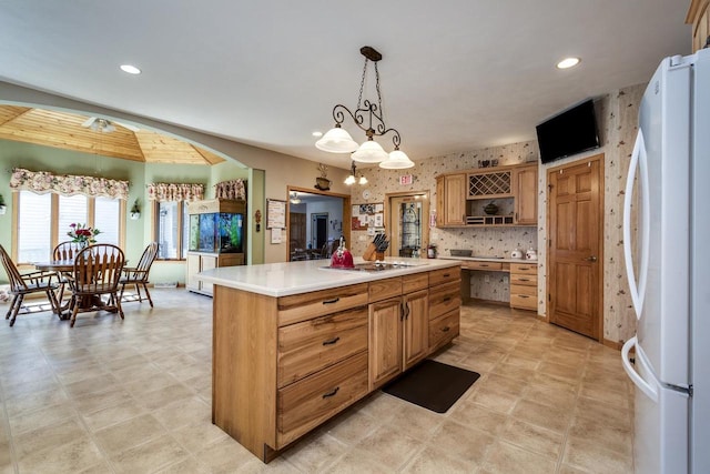 kitchen featuring tasteful backsplash, cooktop, white refrigerator, a center island, and hanging light fixtures