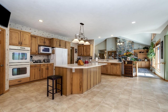 kitchen with a kitchen bar, white appliances, decorative light fixtures, a kitchen island, and lofted ceiling