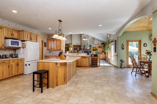 kitchen featuring a kitchen breakfast bar, white appliances, a notable chandelier, a center island, and lofted ceiling