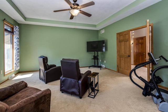 interior space featuring a raised ceiling, ceiling fan, and light colored carpet