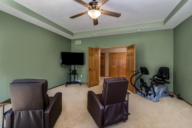 interior space with ceiling fan, light carpet, and a tray ceiling