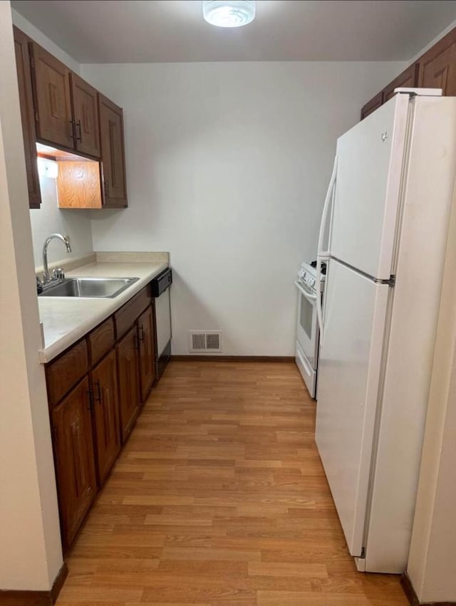 kitchen featuring light wood-type flooring, white appliances, and sink