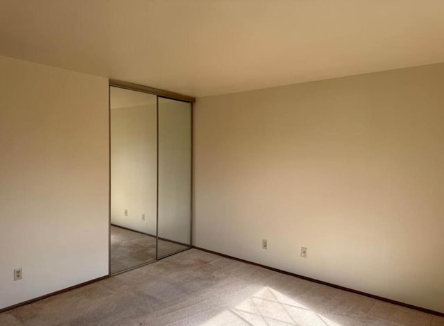 unfurnished bedroom featuring light colored carpet and a closet