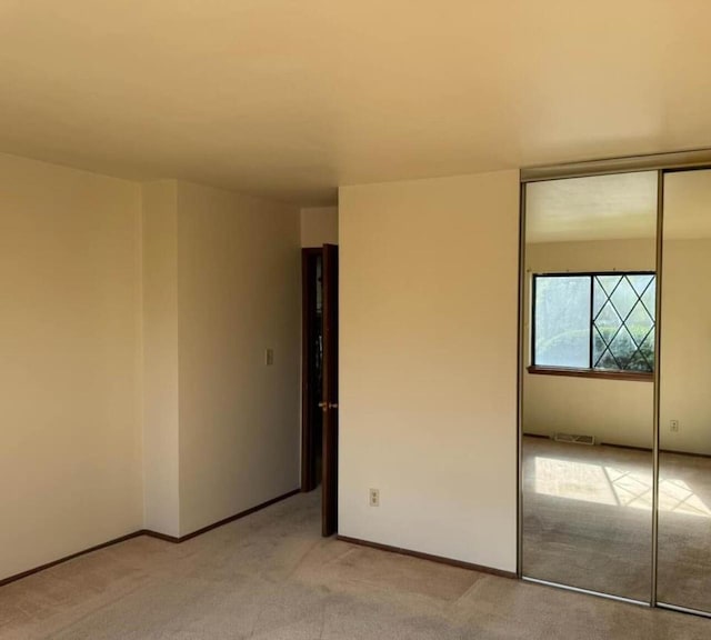 unfurnished bedroom with light colored carpet and a closet