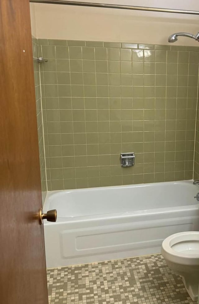 bathroom featuring tile patterned floors, tiled shower / bath combo, and toilet