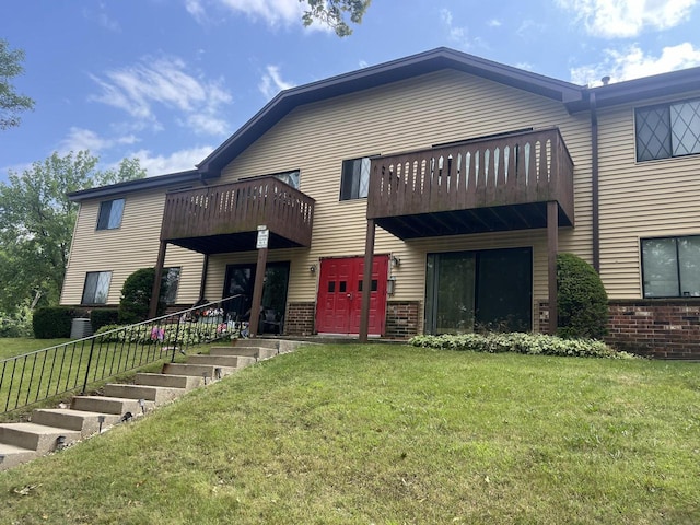 rear view of house with a lawn and a balcony